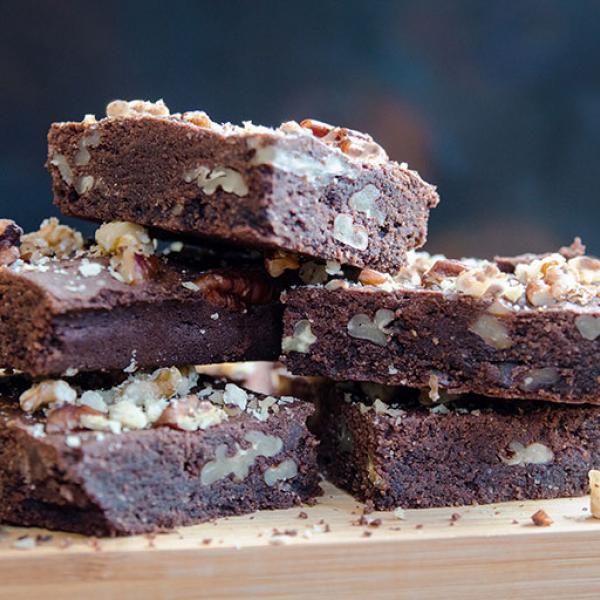 Una pila de brownies de chocolate y nuez, rociados con migas de nuez y nuez triturada, recién sacados del horno